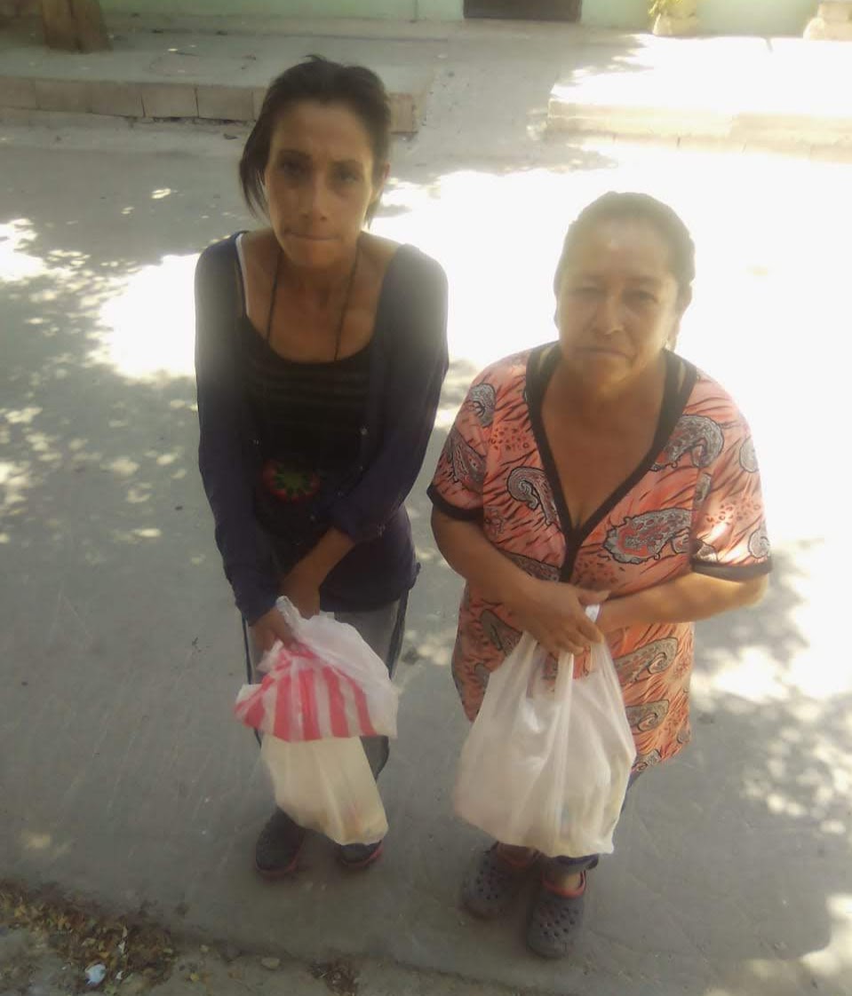 Two Mexican ladies, one older and one younger, each holding a bag of groceries